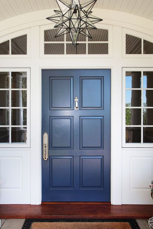 A six-panel wooden door painted in deep navy blue creates timeless elegance for a colonial-style home.